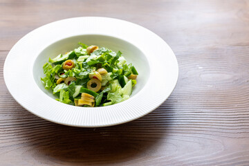 Mediterranean salad with green olives on white plate in close-up