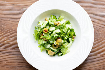 Mediterranean salad with green olives on white plate in close-up