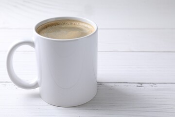 Tasty coffee in cup on white wooden table, closeup. Space for text