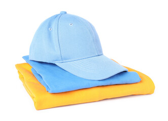 Light blue baseball cap and stack of folded t-shirts isolated on white. Mockup for design