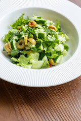 Mediterranean salad with green olives on white plate in close-up