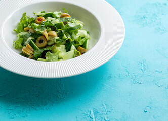 Mediterranean salad with green olives on white plate in close-up