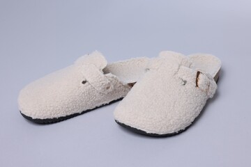Pair of soft white slippers on grey background, closeup