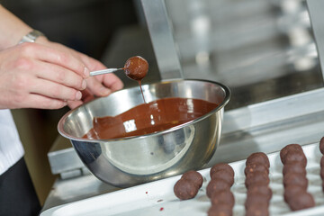 Chef Coating Handmade Chocolate Truffles in Melted Chocolate for Dessert Preparation in Professional Kitchen
