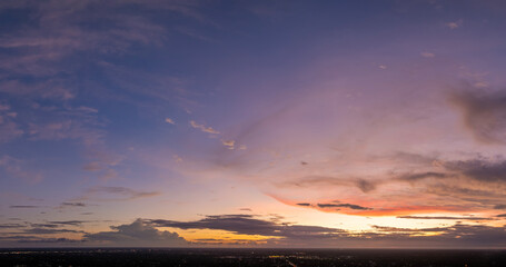Sunset sky over dark land. Bright colorful orange and yellow clouds. Panoramic skyscape