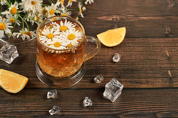 Chamomile tea with lemon in transparent glasses with natural small chamomile flowers on a rustic table, concept of medicinal herbal tea and proper natural nutrition, summer card