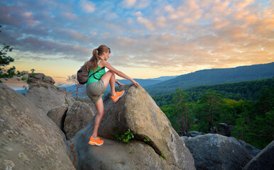 Young woman climbing alone on rocky mountain path. Female hiker enjoying difficult challenge on...