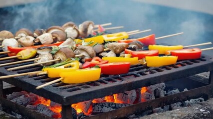 Colorful vegetable and mushroom skewers grilling over smoky charcoal, creating a vibrant outdoor feast