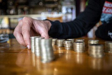Close - up scene. Adult male hand stacking gold coins. Put money coins to stack of coins. Money, Financial, Business Growth concept.	