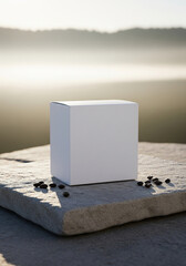 Blank white cube box mockup on a natural stone slab, with scattered coffee beans and a foggy, misty mountain view at sunrise. Perfect for natural or premium product branding.