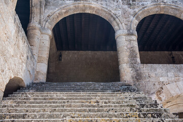 Historic stone courtyard with arched staircases, ancient sculptures in a Mediterranean old town