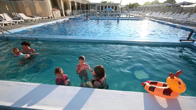 Happy Family Enjoys Fun and Relaxation in a Sunny Outdoor Swimming Pool on Vacation.