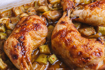 Oven-cooked chicken thighs with chopped vegetables on a tray.