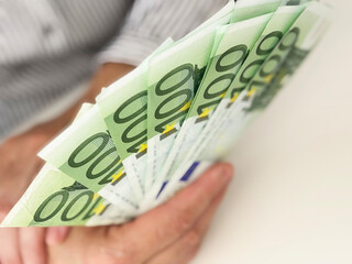 Close-up of a hand holding euro banknotes. Concept of payment, salary, income, savings, finance and...