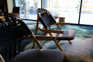 Modern wooden chairs with woven backs and upholstered seats are arranged on a patterned carpet by...