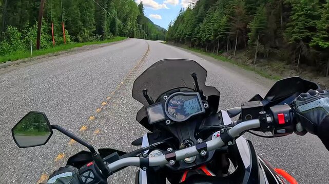 Adventure motorcycle  leaning while riding around twisty highway corners dense forest