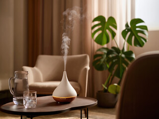 Modern aroma diffuser releasing vapor in bright lounge with armchair, monstera plant and glass pitcher on table