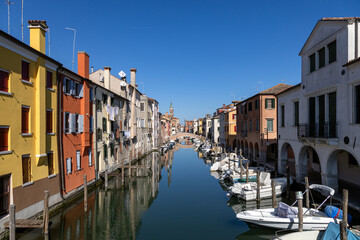View of Canal Vena with moored boats, colorful buildings and reflections in the historic city center in Chioggia, Italy