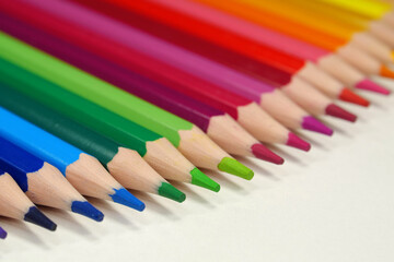 New wooden colored pencils of rainbow colors, perfectly sharpened, lie on table
