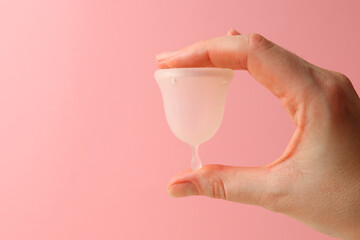 Eco-friendly menstrual cup in female hands on bright background