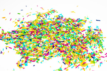 Pile of colorful sprinkles on a white background. The sprinkles are in various colors and sizes, creating a vibrant and playful atmosphere