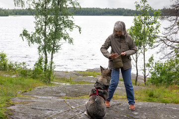 Woman dog behaviorist training dog outdoors near lake