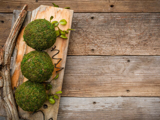 Rustic overhead image of weathered farmhouse wood plank table with decorative moss balls on a board in a shabby chic country setting. 
