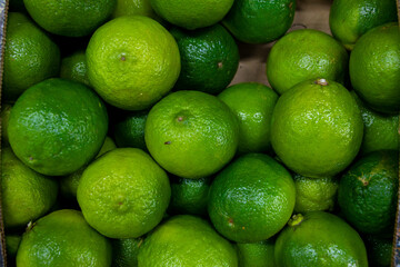 Lots of green lime. Lime in a box. Sale of lime at the market and store. Background. Top view. Conservation for the winter. Vegetarianism.