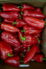 Many ripe red sweet peppers. Paprika. Sweet peppers in a box. Sale of peppers at the market and...