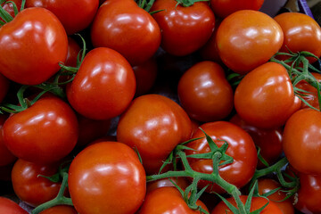 Many ripe red tomatoes. Cherry tomatoes. Pink tomatoes. Tomatoes in a box. Sale of tomatoes at the market and store. Background. Top view. Concentration sale at the market and store. Farm products. 