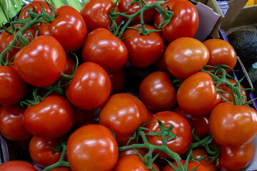 Many ripe red tomatoes. Cherry tomatoes. Pink tomatoes. Tomatoes in a box. Sale of tomatoes at the market and store. Background. Top view. Concentration sale at the market and store. Farm products. 