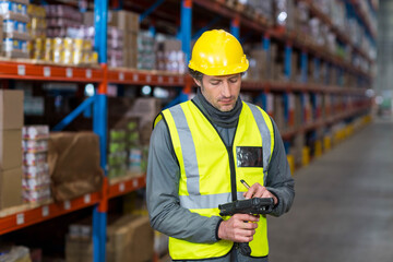 Male warehouse associate standing in warehouse checking inventory on handheld scanner with stylus