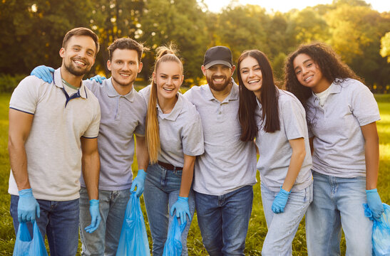 Group of happy young multiethnic people volunteers embracing eco friendly lifestyle and picking up litter outside in city park helping save planet caring about nature. Environment protection concept