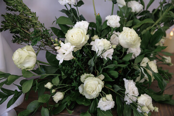 Elegant arrangement of white roses and carnations with lush green foliage, capturing a sophisticated and serene atmosphere. Ideal for weddings, events, or home decor inspiration.