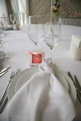 Close-up of a beautifully set wedding table featuring a white napkin elegantly folded on a plate, surrounded by wine glasses and cutlery, conveying a sophisticated dining experience.