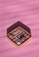 Set of chocolate craft candy in box on pink background