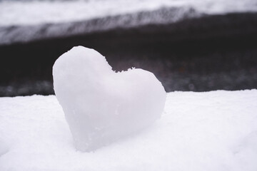 Heart of snow on white snow in winter, soft focus, close-up. Holiday valentine, romantic background.