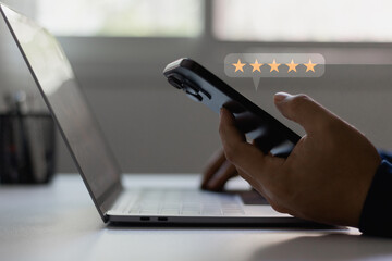 Customer service experience and business satisfaction survey concept. A man using a smartphone and laptop computer with a five-star icon for online feedback and rating review satisfaction service.