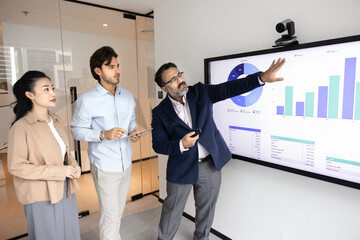Corporate education and active learning. Mature businessman mentor teach diverse young colleagues interns at digital board with business data graphs explain project strategy show growth opportunities