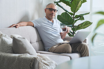 Confident hispanic freelancer working from home, drinking coffee and using laptop