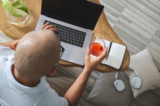 Mature freelancer working from home, enjoying coffee and using laptop on sofa