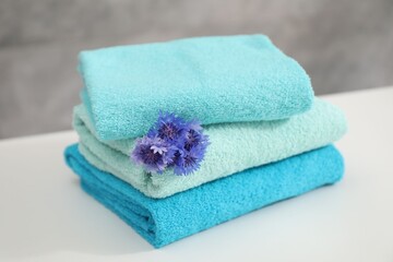 Stack of colorful towels and flowers on white table, closeup
