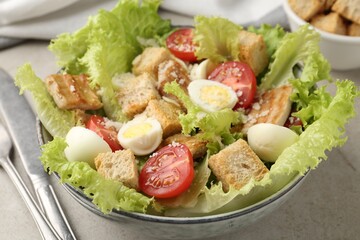 Delicious salad with croutons, chicken, quail eggs, tomato and cheese on grey table, closeup