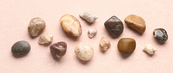 Many pebble stones and seashells on pink background