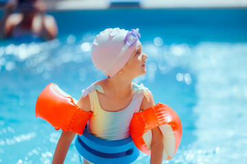 Little Girl Taking Swimming Lessons with Safety Water Gear in a Pool. Little child wearing protective gear for her swimming during summer vacation