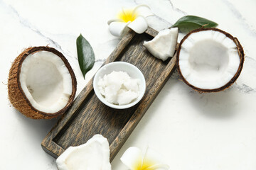 Wooden tray, flowers and bowl with natural coconut oil on marble background, closeup