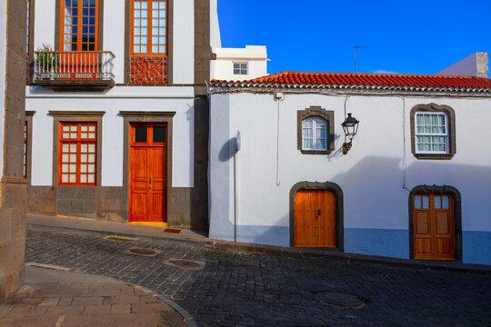 Charming street scene showcasing traditional architecture of Canary Islands with vibrant whitewashed buildings and wooden doors. Historic old town street of Arucas city from Gran Canaria