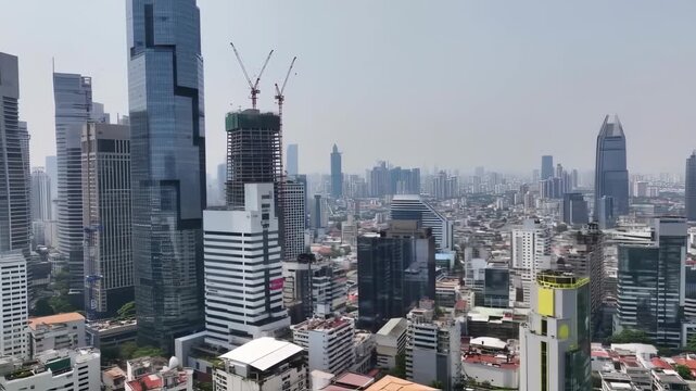 A sprawling city panorama, showcasing numerous high-rise buildings, some under construction, with cranes visible