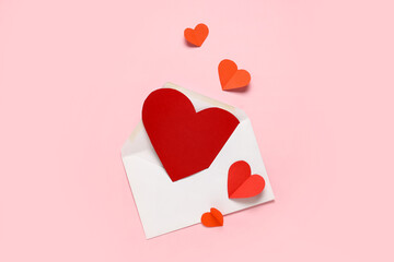 Envelope with red paper hearts on pink background. Valentine's Day celebration