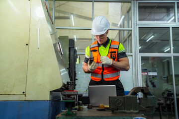 A man in a yellow and black vest is working on a machine. Professional engineer engaged in...